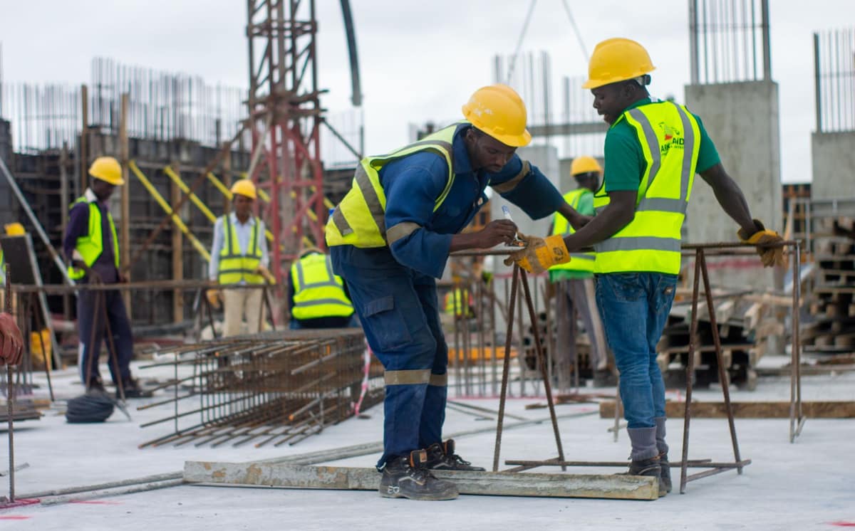 A crew in hard hats and hi-vis vests setting reinforcing steel on a building site