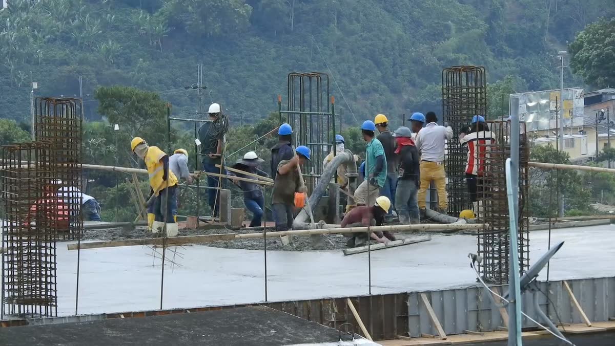 Crew members in hard hats working on a concrete deck at a building site